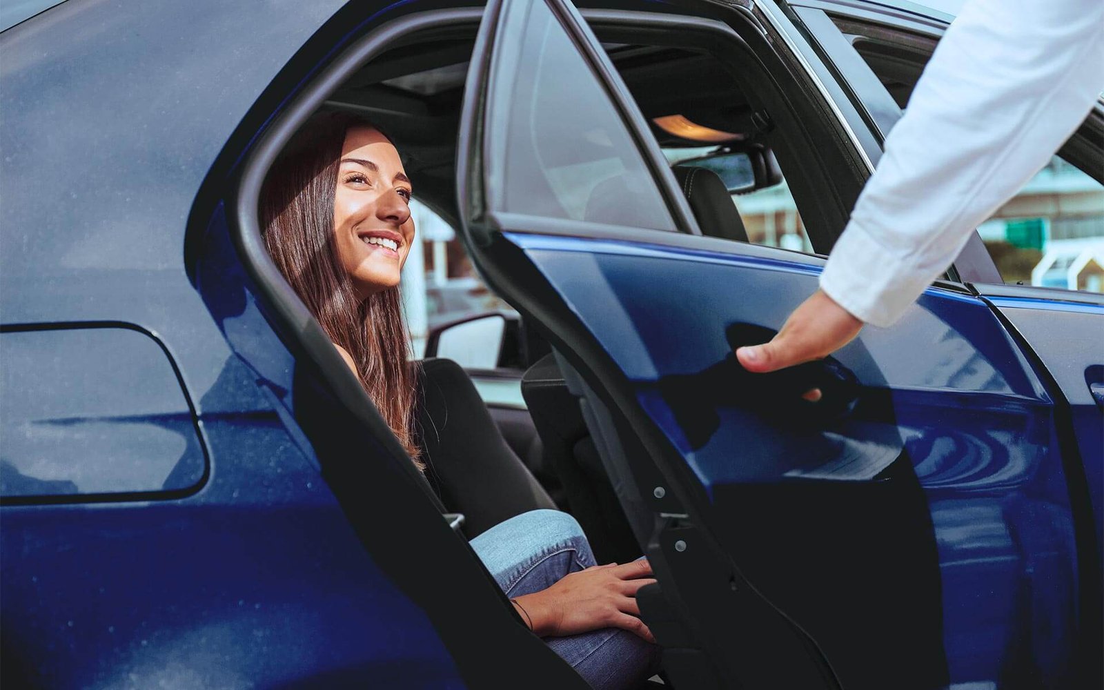 taxi driver open a car door to a smiling woman in a taxi cab